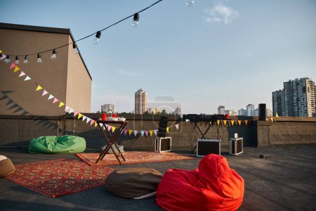 object photo of outdoor rooftop with red carpets and DJ equipment with plates and cups on table