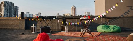 Objektfoto von der Dachterrasse mit lebendigen Teppichen und DJ-Equipment mit roten Tassen auf dem Tisch, Banner