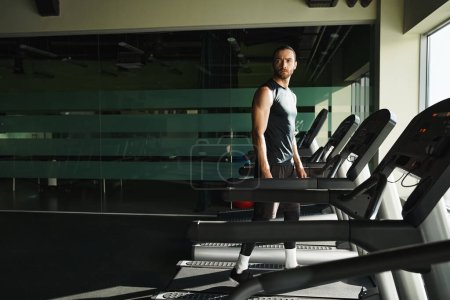 Ein athletischer Mann in aktiver Kleidung steht selbstbewusst auf einem Laufband im Fitnessstudio, Konzentration und Entschlossenheit im Gesicht.