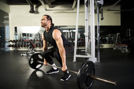 Ein fokussierter Mann in aktiver Kleidung macht eine Kniebeuge mit einer Langhantel in einem Fitnessstudio und demonstriert Stärke und Entschlossenheit.