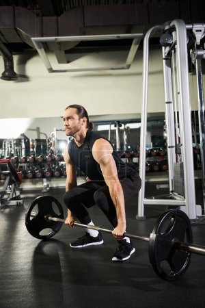 A man in active wear squats with a barbell in a gym.