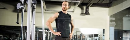 Téléchargez les photos : An athletic man in active wear standing in a gym, hands on hips. - en image libre de droit