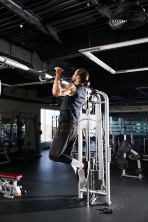 Un hombre atlético en ropa activa haciendo un pull up en una máquina en un gimnasio.