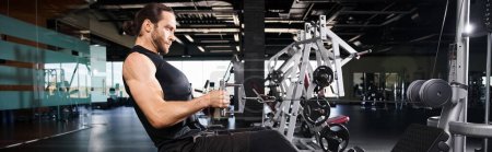 Sportlicher Mann in aktiver Kleidung bei einem Workout mit einem Gerät in einem Fitnessstudio.