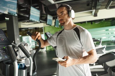 Téléchargez les photos : Active man in gym attire jogging on treadmill while immersed in music through headphones. - en image libre de droit