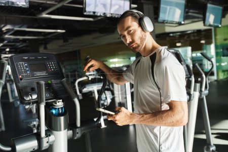 An athletic man in active wear is jogging on a treadmill, fully immersed in his workout with headphones on.