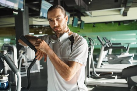 Téléchargez les photos : A fit man in activewear is using a treadmill in a gym for his workout routine. - en image libre de droit