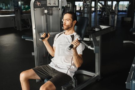 Ein athletischer Mann in aktiver Kleidung sitzt auf einer Bank in einem Fitnessstudio und pausiert zwischen den Sets mit konzentriertem Gesichtsausdruck..