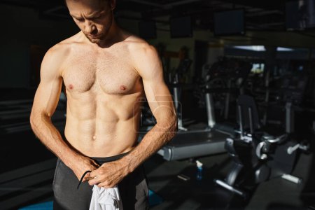 Ein muskulöser Mann zeigt seine Stärke beim Training ohne Hemd in einem Fitnessstudio.
