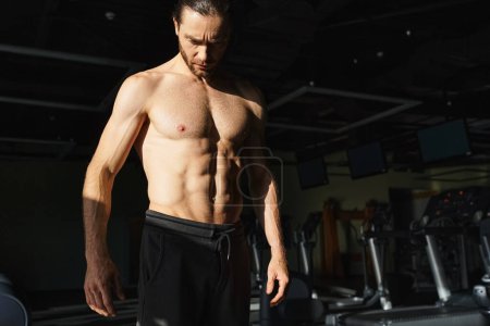 A muscular man without a shirt standing in a gym environment, actively engaged in working out and physical training.