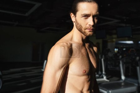 Ein muskulöser Mann ohne Hemd trainiert in einem Fitnessstudio und zeigt seinen starken Körperbau und seine Hingabe zur Fitness..