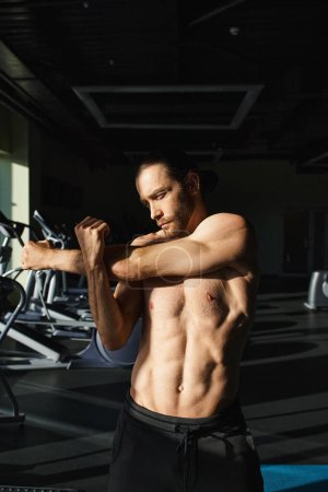 Ein hemdloser, muskulöser Mann, der seine Muskeln in einem Fitnessstudio spielen lässt und seine Stärke und Hingabe zur Fitness demonstriert.
