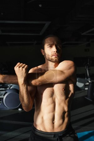 A shirtless man diligently works out in a gym, focused on sculpting his muscles through strength training.
