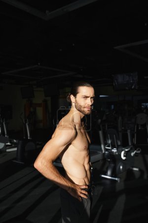 Ein muskulöser Mann ohne Hemd, der seine Stärke demonstriert, während er im Fitnessstudio steht.