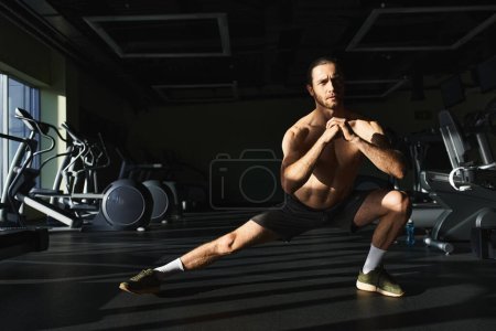 Muskelprotz ohne Hemd hockt auf einem Bein in einem Fitnessstudio.