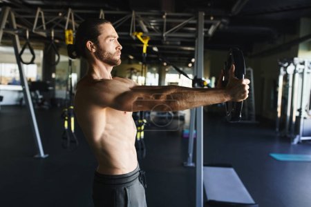 A muscular man without a shirt is holding a barbell in a gym, showcasing his strength and dedication to fitness.