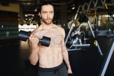 A shirtless man displaying his immense strength, holding two dumbbells, in the intense atmosphere of a gym.