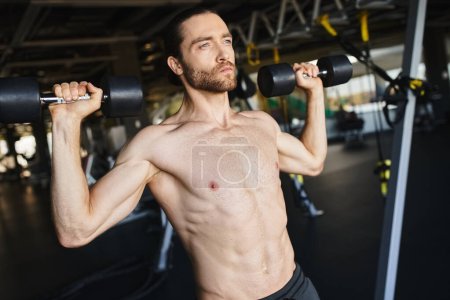 Foto de Un hombre musculoso sin camisa sosteniendo dos pesas en un gimnasio, mostrando su rutina de entrenamiento y fuerza física. - Imagen libre de derechos