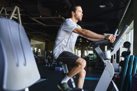 A muscular man is energetically cycling on a stationary bike at the gym.