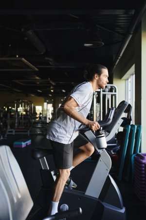 Muscular man pushing his limits, sprinting on a stationary bike in a modern gym environment.