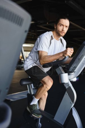 A muscular man energetically pedaling a stationary bike in a gym.