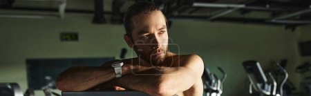 Un hombre musculoso sin camisa, entrenando intensamente en un gimnasio.