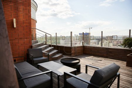 Téléchargez les photos : Un cadre de balcon confortable avec deux chaises et une table, donnant sur un paysage urbain animé ci-dessous - en image libre de droit