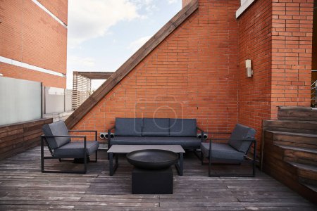 A stylish patio featuring a comfortable couch, inviting chairs, and a sleek coffee table set against a backdrop of tranquility