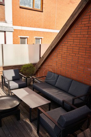 A tranquil patio adorned with a stylish couch, a sleek table, and cozy chairs, inviting relaxation and enjoyment