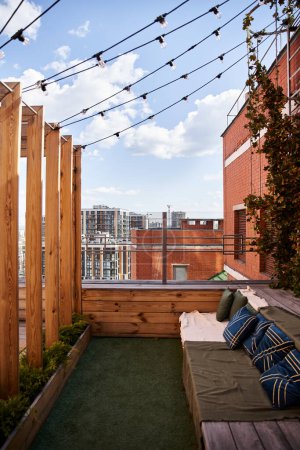 A small balcony adorned with a comfortable couch is illuminated by warm string lights, creating a serene and inviting atmosphere