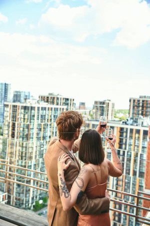 Ein junges Paar stößt mit erhobenen Gläsern vor der Kulisse einer geschäftigen Stadtsilhouette auf das Leben an.