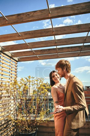 A man and a woman standing on a rooftop, looking out at the city skyline