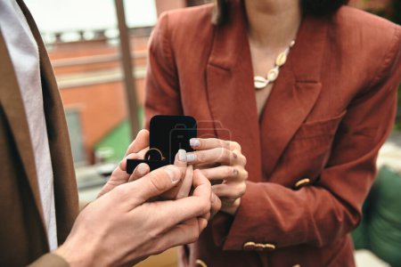 Eine Person auf gebeugten Knien bietet ihrem Partner einen Ring an, der einen herzerwärmenden Vorschlag festhält.