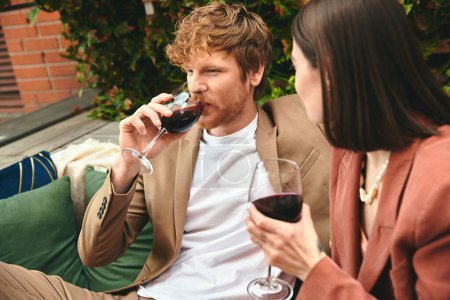 Photo for A man and a woman enjoy a cozy evening on a couch, sipping wine together - Royalty Free Image