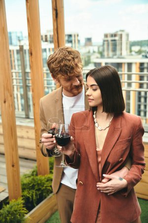 Téléchargez les photos : Un homme et une femme se tiennent gracieusement debout, tenant un verre de vin. Ils respirent la sophistication et l'intimité dans leur moment partagé - en image libre de droit