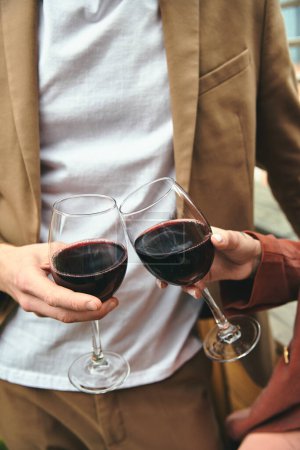 Un homme élégant avec un verre dans chaque main rempli de vin rouge, mettant en valeur l'élégance et la sophistication