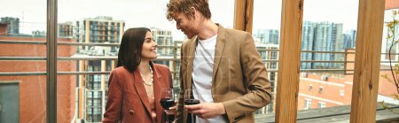Photo for A man and a woman stand together, she holds a wine glass. The couple appears sophisticated and relaxed in their surroundings - Royalty Free Image