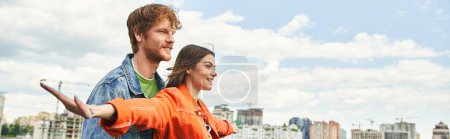Photo for A stylish couple stands together, gazing at the stunning cityscape behind them, showcasing a modern love story in an urban setting - Royalty Free Image