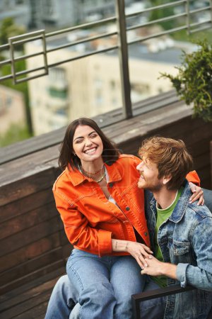 Woman and man sit peacefully atop a wooden bench, enjoying each others company in a tranquil setting