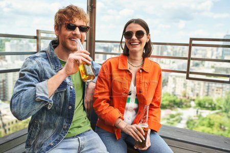 A man and a woman enjoy each others company on a bench, sipping beer together