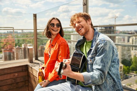 Ein Mann und eine Frau sitzen auf einem Gebäude und genießen an einem sonnigen Tag den Blick auf die darunter liegende Stadt