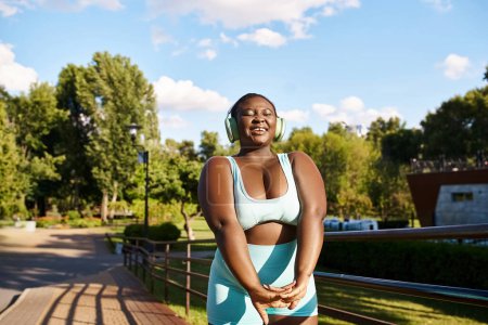 Une Afro-Américaine aux bras croisés se tient sur un banc, embrassant sa force et sa positivité corporelle.
