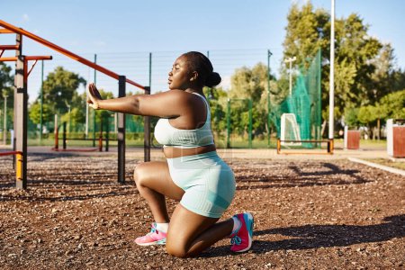 Una mujer afroamericana en ropa deportiva en cuclillas frente a un parque infantil, que encarna la positividad y la fuerza del cuerpo.