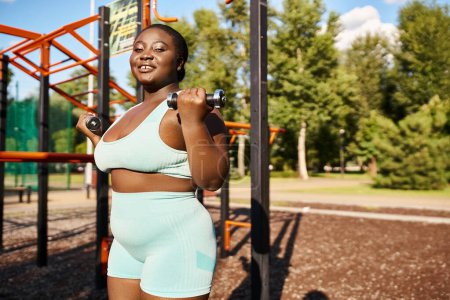 African American woman in sportswear confidently exercising in front of gym equipment.