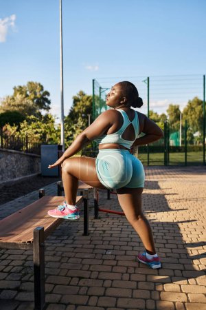 An African American woman in sportswear sits leisurely on a bench, embracing a moment of calm outdoors, working out
