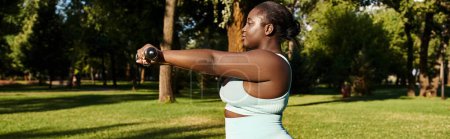 An African American woman in a white tank top confidently holds a black dumbbells outdoors, embodying body positivity and strength.
