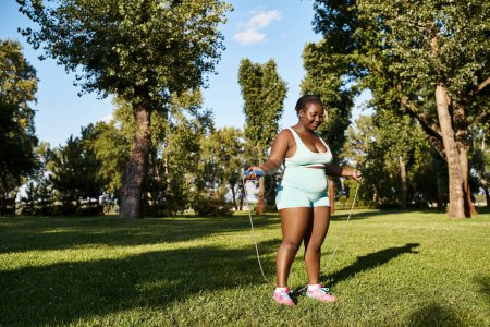Una mujer afroamericana en ropa deportiva explora su potencial corporal, empuñando con gracia una cuerda para saltar al aire libre.