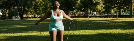 Eine Afroamerikanerin mit kurvigem Körper steht im Freien und trägt einen kurzen Rock mit Springseil