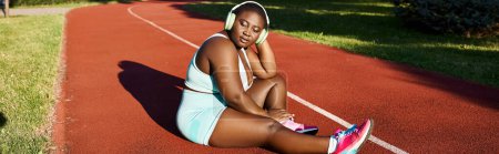 Téléchargez les photos : Femme afro-américaine en tenue de sport, assise en toute confiance sur le tribunal - en image libre de droit