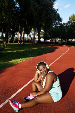Photo for An African American woman in sportswear sitting on a tennis court - Royalty Free Image